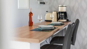 Une cuisine avec un plan de travail en bois, une machine à café, une bouteille et un verre à vin.