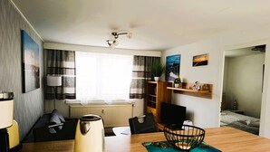 Un salon moderne avec un canapé, une table basse, une bouilloire et un téléviseur.