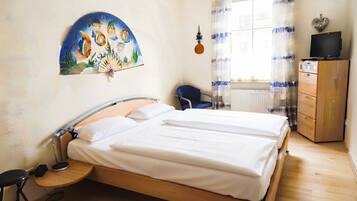 Een slaapkamer met een bed, een stoel, een bureau, een dressoir en een schilderij aan de muur.