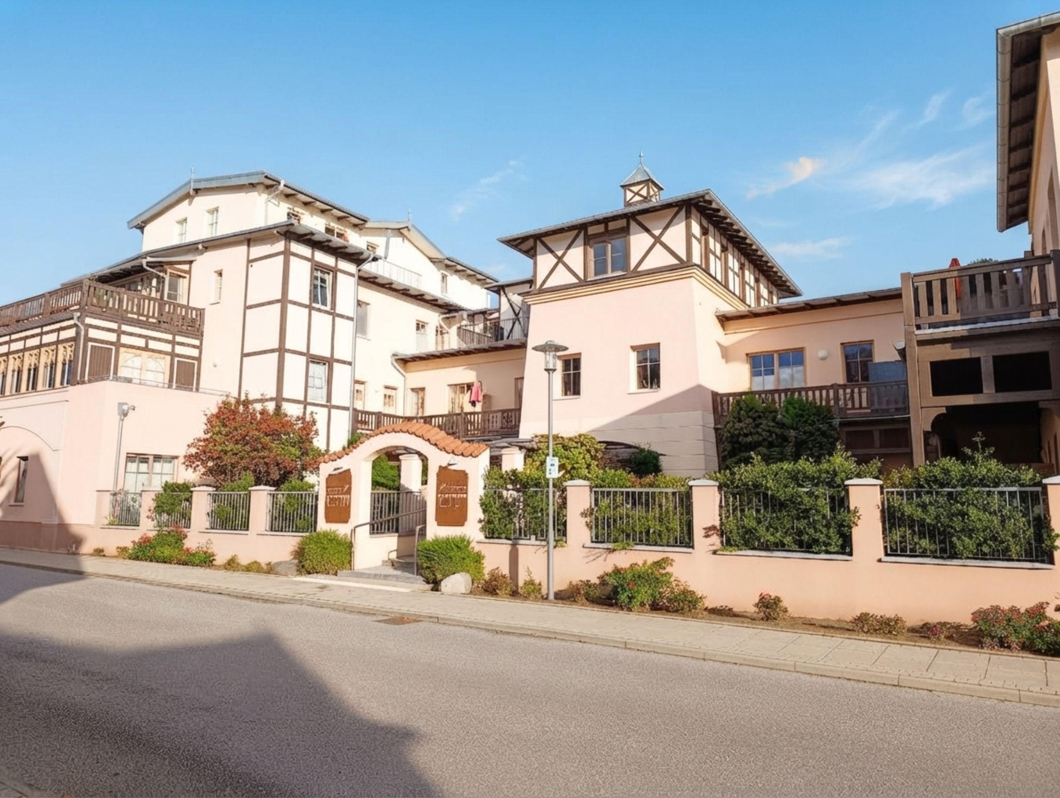 A row of traditional European-style buildings with a central entrance, a street in front, and a clear sky.