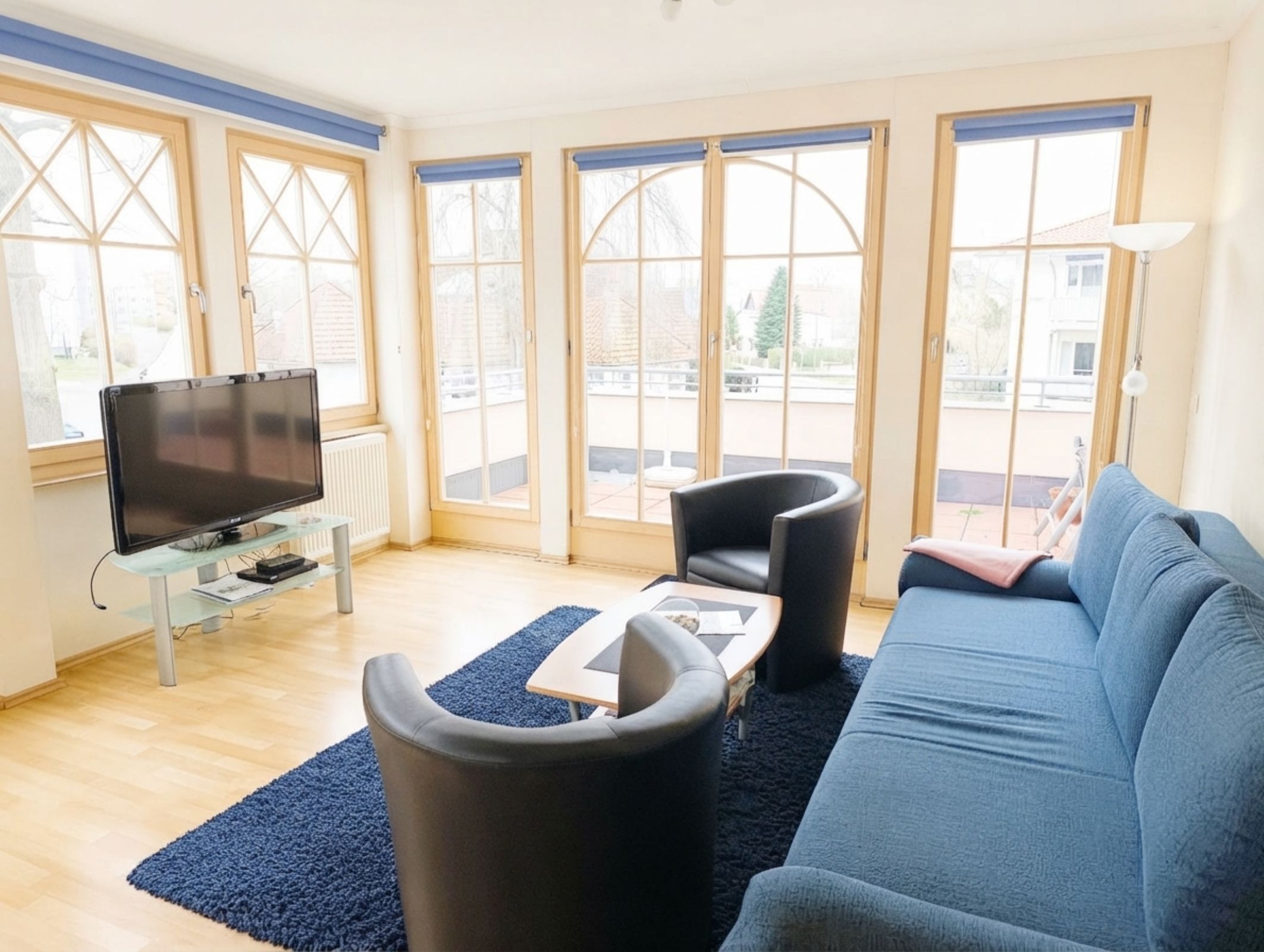 Een moderne woonkamer met een flatscreen televisie, een bank, twee fauteuils en een salontafel.
