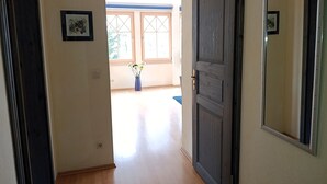 A hallway with a wooden floor, a dark wooden door, and a window with a view of the outdoors. - Residence Starfish Ws.03 - Starfish Ws.03 (Kühlungsborn)