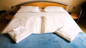 A neatly made bed with white linens and two folded towels, a wooden headboard, and bedside lamps. - Residence Starfish Ws.03 - Starfish Ws.03 (Kühlungsborn)