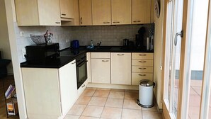 A kitchen with light wooden cabinets, a black countertop, a stove, and a trash can. - Residence Starfish Ws.03 - Starfish Ws.03 (Kühlungsborn)