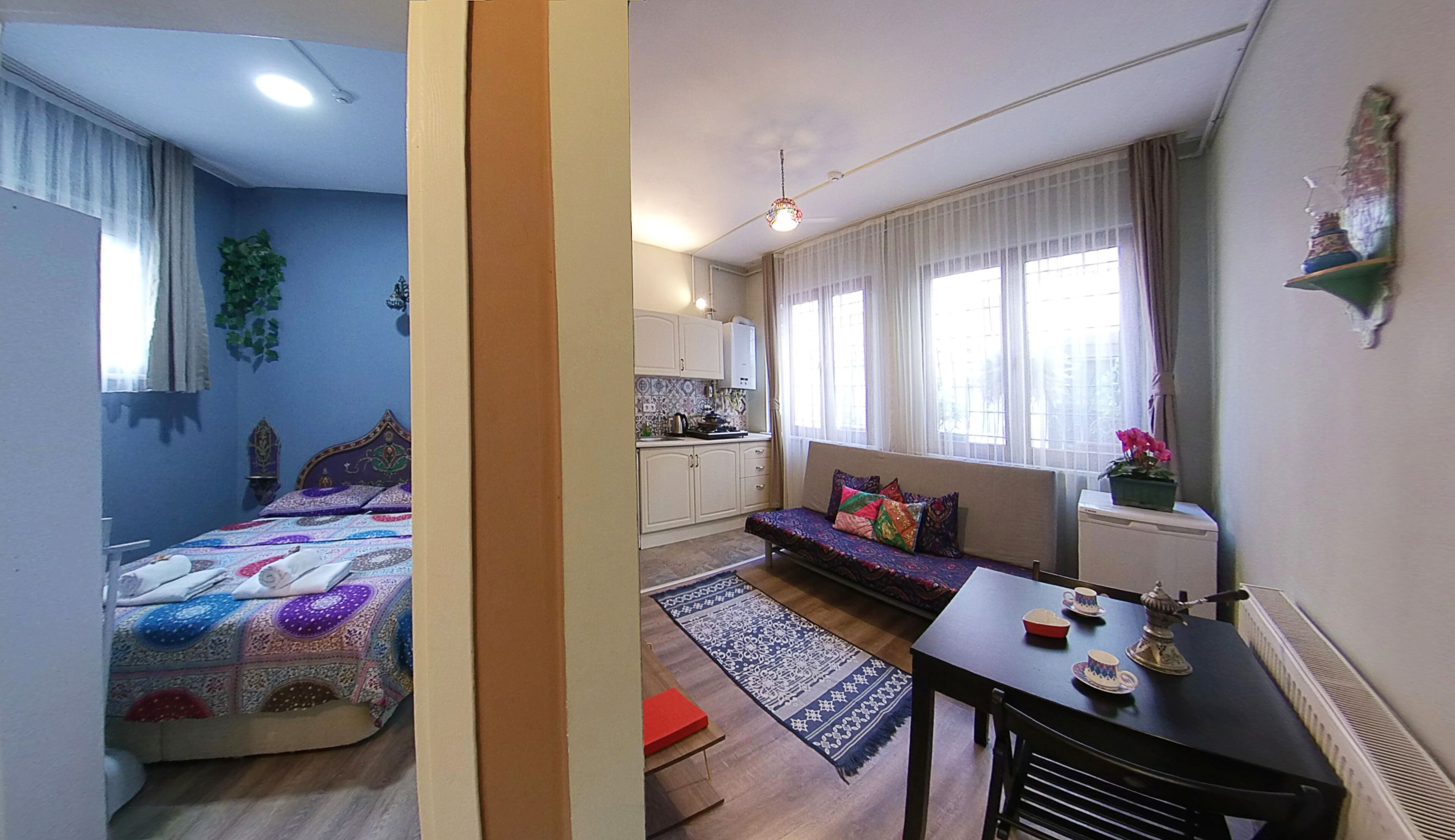 Um espaço compacto com cama, sofá, cozinha pequena e mesa de jantar.