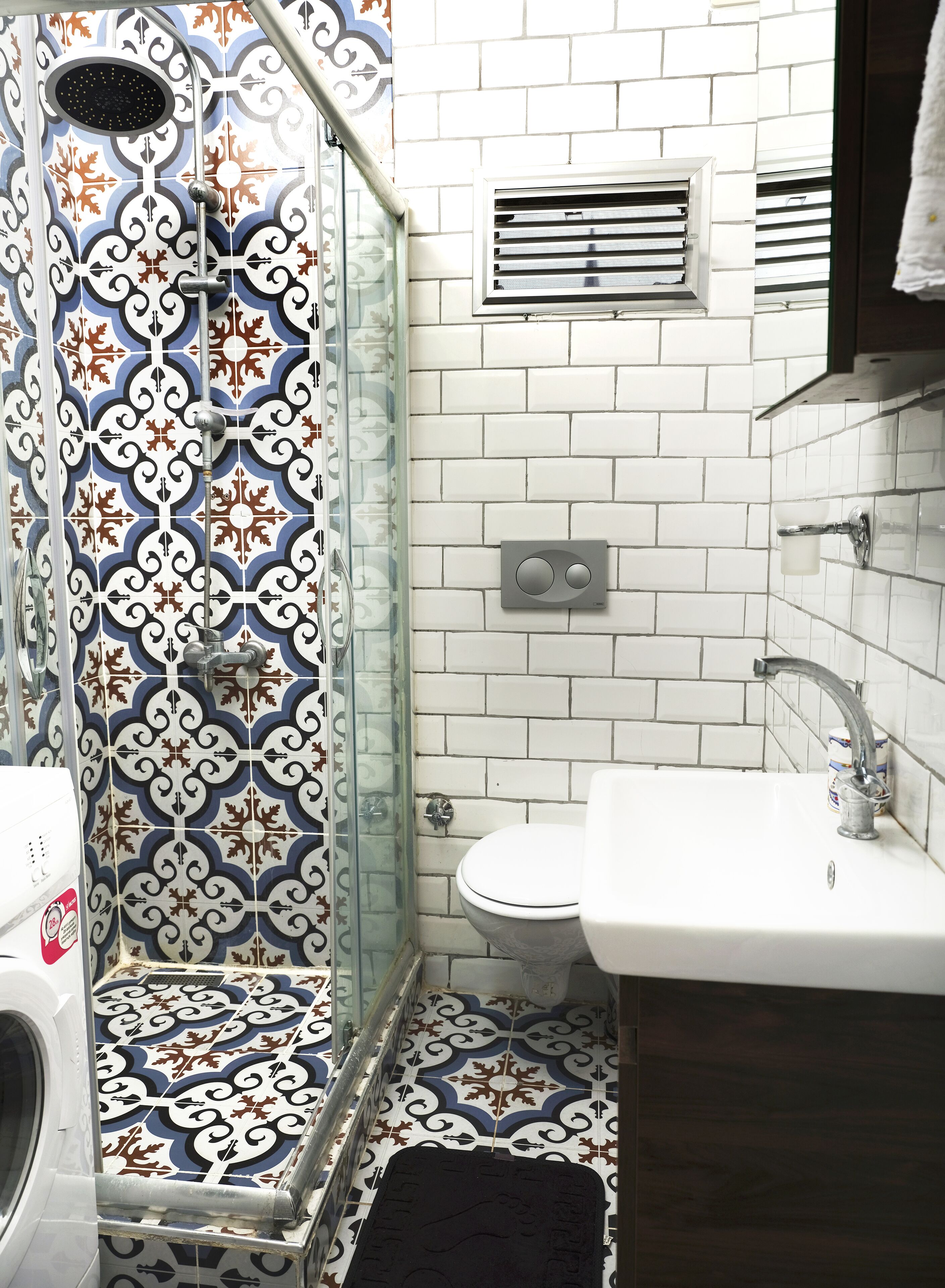 Une salle de bain avec douche, toilettes, lavabo et carrelage décoratif.