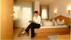 Una habitación con una cama, una lámpara de lectura y una ventana con cortinas.