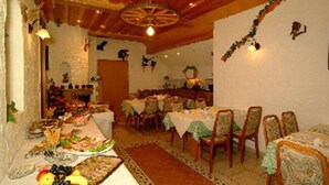 Comedor con varias mesas dispuestas para una comida, vigas de madera en el techo y una lámpara de araña.