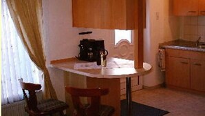 Una cocina compacta con armarios de madera, una mesita y una silla.