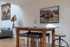 Un comedor con una mesa de madera, dos taburetes negros acolchados y un taburete de bar.