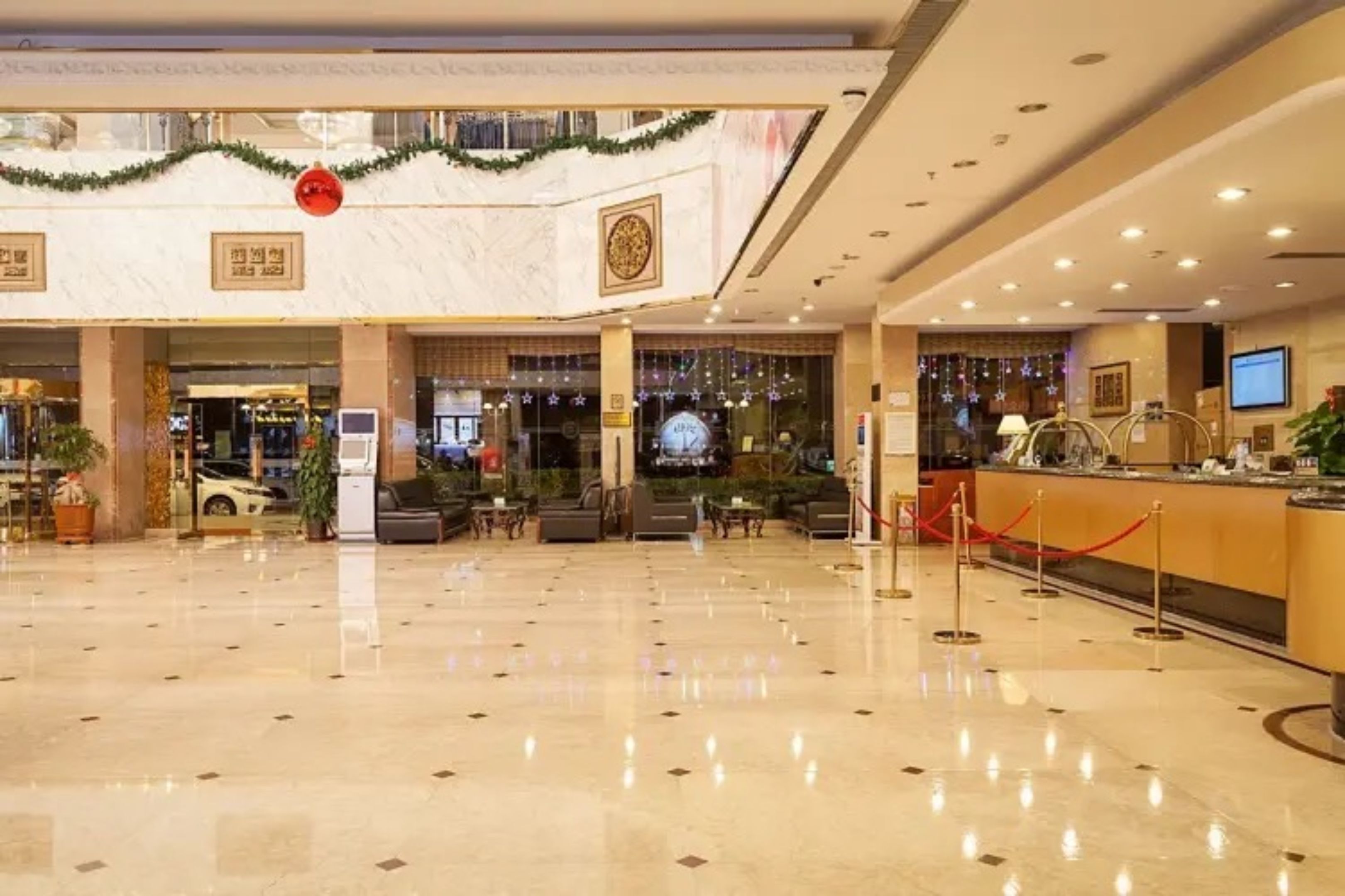 A spacious lobby with a marble floor, a reception desk, and a Christmas garland.