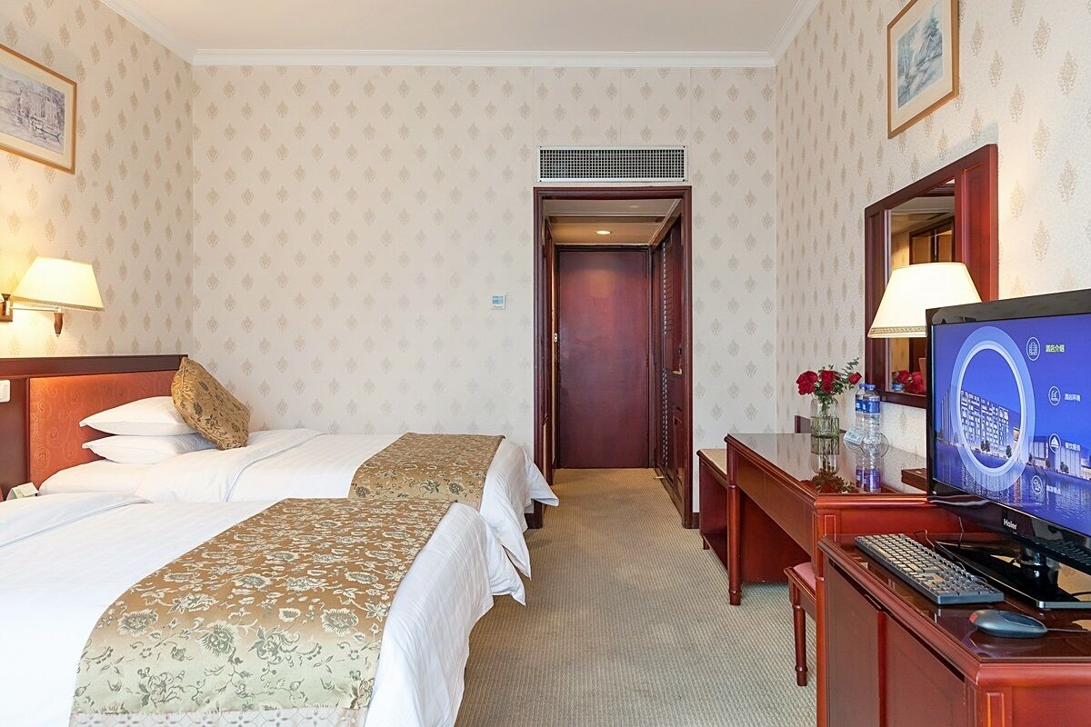 Una habitación de hotel con dos camas, un escritorio con computadora y televisión.