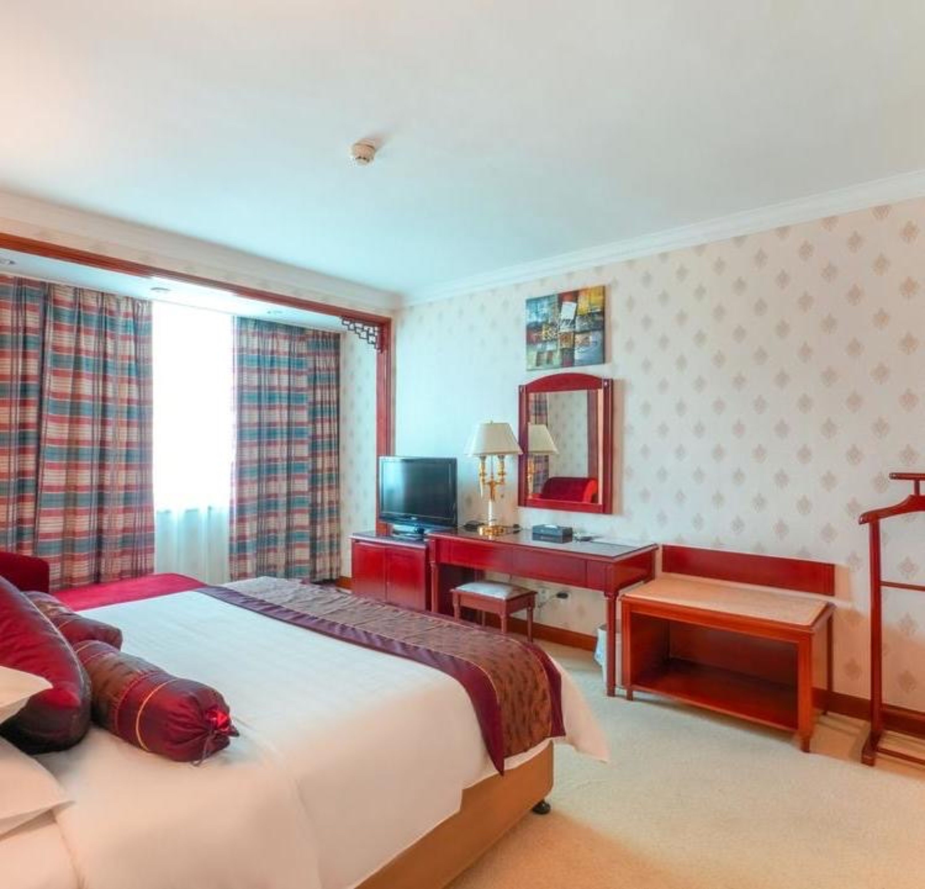 Habitación de hotel con cama, escritorio, silla, televisor y armario.