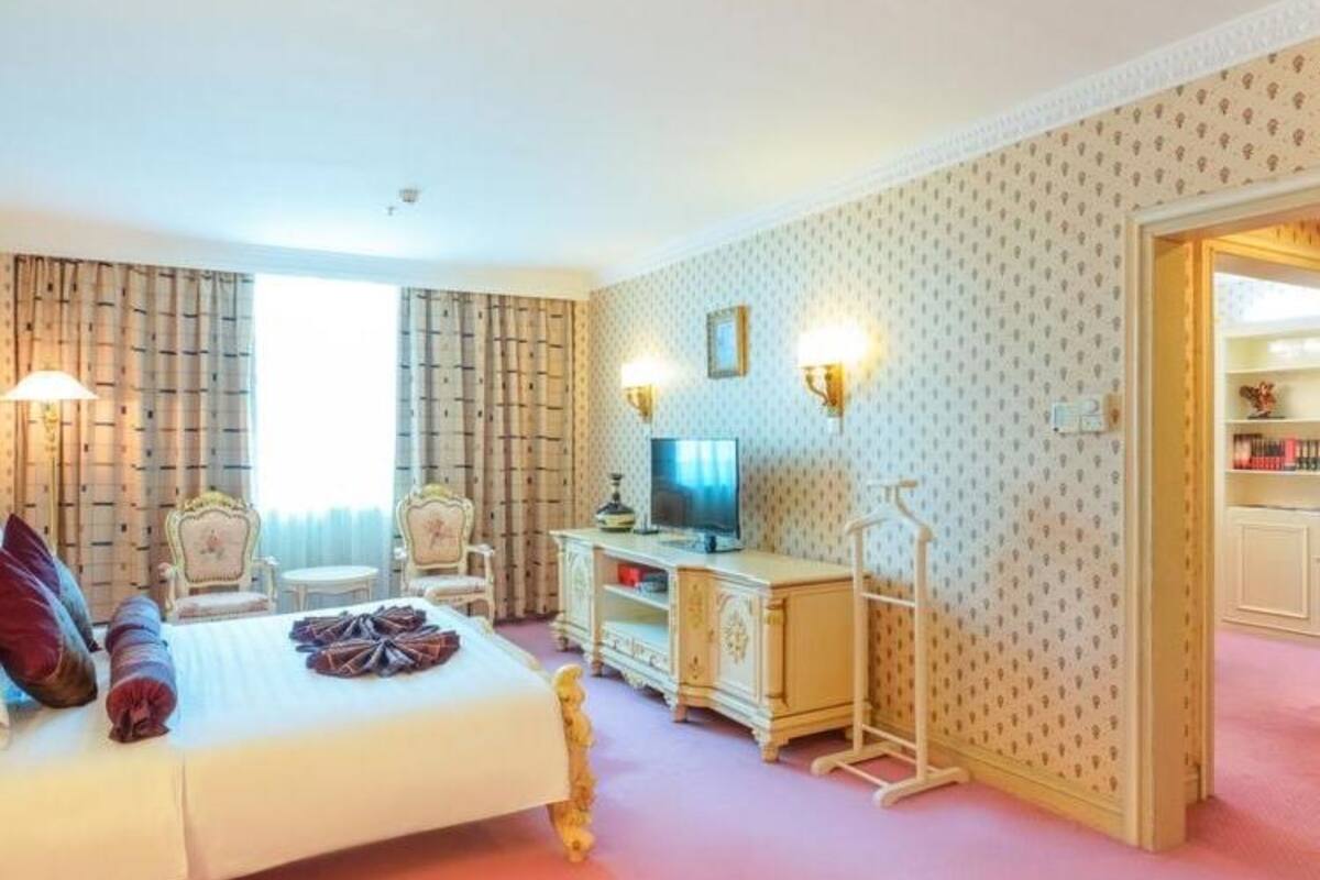 Una habitación de hotel con cama, escritorio, televisor y armario.
