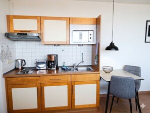 Eine kleine Küche mit Holzausstattung, einer eingebauten Mikrowelle und einer Kaffeemaschine.