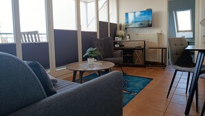 Ein modernes Wohnzimmer mit einer Couch, einem Couchtisch und einem an der Wand befestigten Fernseher.
