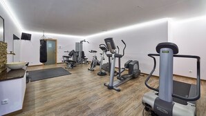 A gym with various exercise equipment, a stone sink, and a punching bag. - Gartenhotel Daxer (Zell am See)