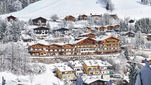 A snow-covered resort with multiple buildings, including a large lodge with balconies and smaller cabins. - Gartenhotel Daxer (Zell am See)