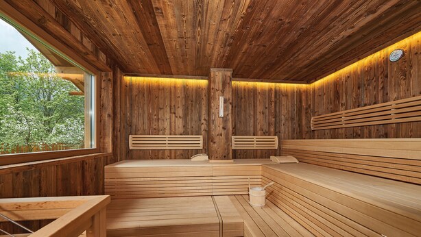 A wooden sauna with benches and a wooden table. - Gartenhotel Daxer (Zell am See)