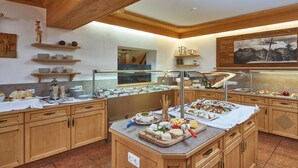 A buffet setup with various food items and a glass display case. - Gartenhotel Daxer (Zell am See)