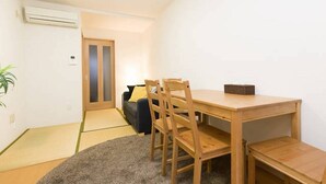 Una habitación con una mesa de madera, sillas, un sofá y una planta pequeña.