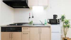 Una cocina compacta equipada con estufa, pileta, microondas y un refrigerador pequeño.