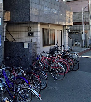 Bicycles parked outside a building with a tiled facade and a clock above the entrance.