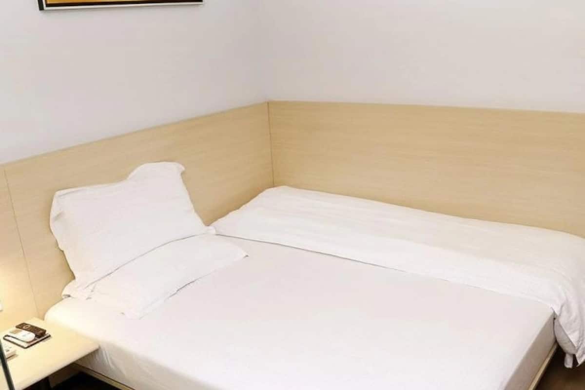 Un lit simple avec une tête de lit en bois dans une chambre d’hôtel.