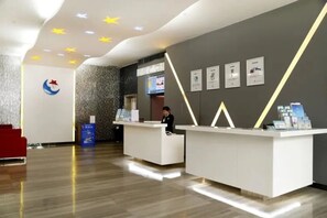 A modern reception area with a receptionist, a digital screen, and a logo on the wall. - Wenxin Hotel Shenzhen (Guangzhou)