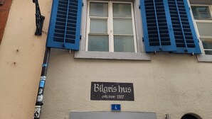 A building with blue shutters, a sign reading "Bilaris bus", and a wooden door. - ZH Schmidgasse I - Hitrental Apartment (Zürich)