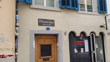 Un edificio con puerta de madera, contraventanas azules y un letrero que dice "Bilgis hus".