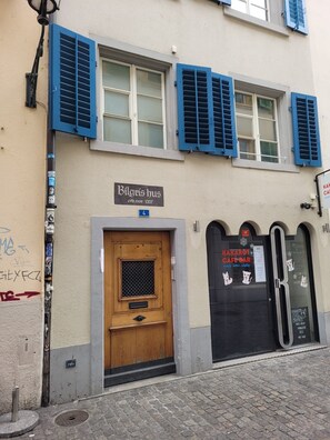 A building with a sign 'Bilgris hus' and a door with a mesh window.