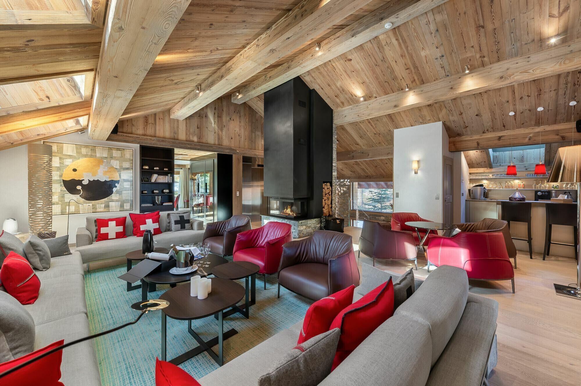 A spacious living area with a fireplace, modern furniture, and a view of the kitchen.