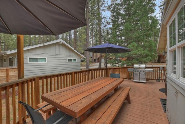 A wooden deck with a picnic table and benches, surrounded by a wooden railing.
