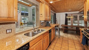 Una cocina con armarios de madera, encimeras de granito, un lavamanos de acero inoxidable y un horno empotrado.