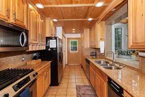 A modern kitchen with wooden cabinets, stainless steel appliances, and a granite countertop.