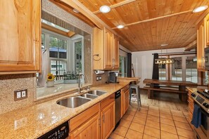 Una cocina con armarios de madera, encimeras de granito, lavavajillas integrado y un ventanal grande.