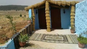 Un petit bâtiment rustique, doté d’un toit de chaume et d’une façade bleue.