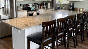 Una cocina moderna con una isla grande, electrodomésticos de acero inoxidable y un comedor con sillas de madera.