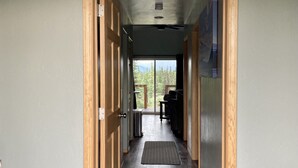 Un pasillo con puertas de madera, un ventilador de techo y vistas a una terraza y zona exterior.