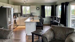 Una cocina amplia con una isla central, armarios blancos y un comedor con mesa y sillas.