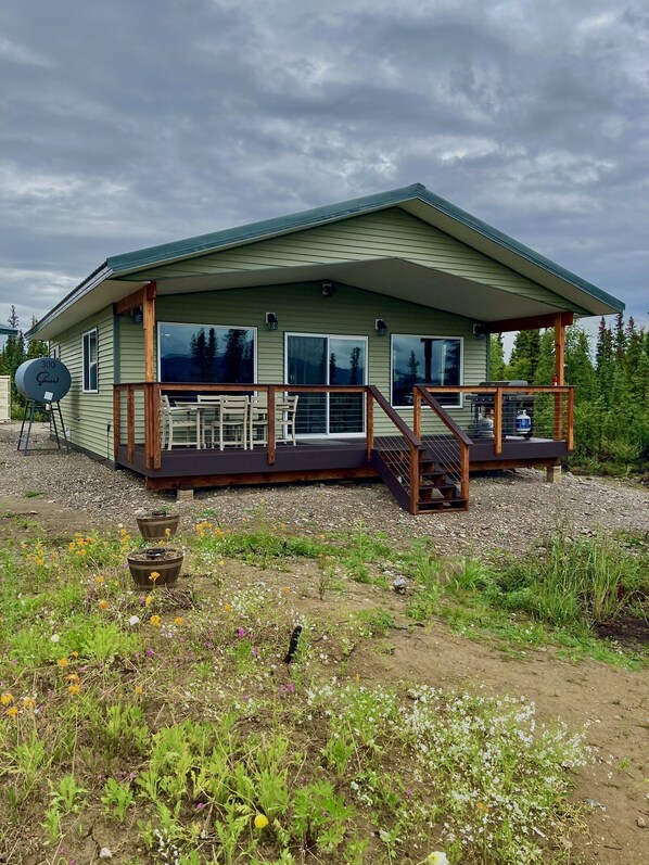 Einbungalow mit einer überdachten Terrasse, großen Fenstern und einem Kiesweg.