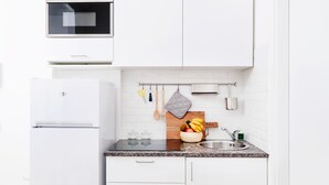 A modern kitchen with white cabinets, a built-in oven, a granite countertop, a wooden cutting board, and a stainless steel sink. - Orti - Modern Apartment Porta Romana (Milan)