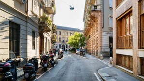 A narrow street lined with historic buildings, parked motorcycles, and a cable car overhead. - Orti - Modern Apartment Porta Romana (Milan)