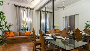 A dining area with a glass table, wooden chairs, and a sofa with orange cushions. - Guercino - Apartment Porta Garibaldi (Milan)