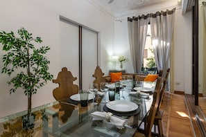 Un coin repas avec une table en verre, des chaises en bois et une plante en pot.