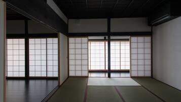 Una habitación tradicional japonesa con suelo de tatami, puertas correderas shoji y techo oscuro.