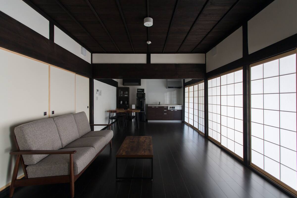 Una habitación tradicional japonesa con suelo de tatami, techo de madera bajo y puertas correderas shoji.