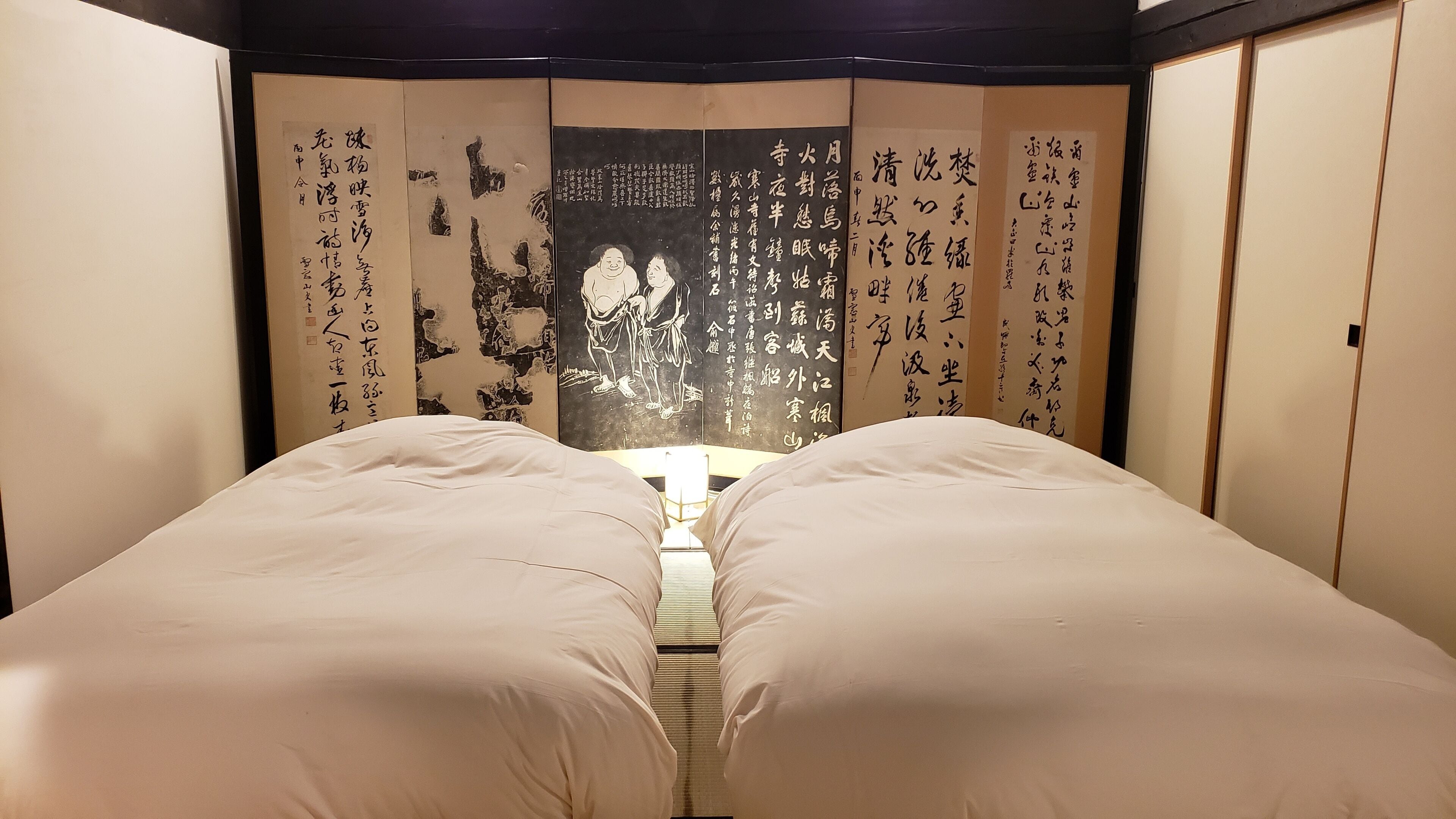 A traditional Japanese room with tatami flooring, a low table, and sliding doors with calligraphy.