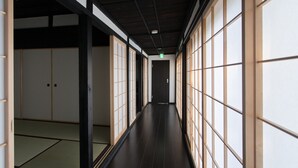 A traditional Japanese hallway with tatami mat flooring, sliding doors, and a dark wooden ceiling. - Solii (Ishikari)